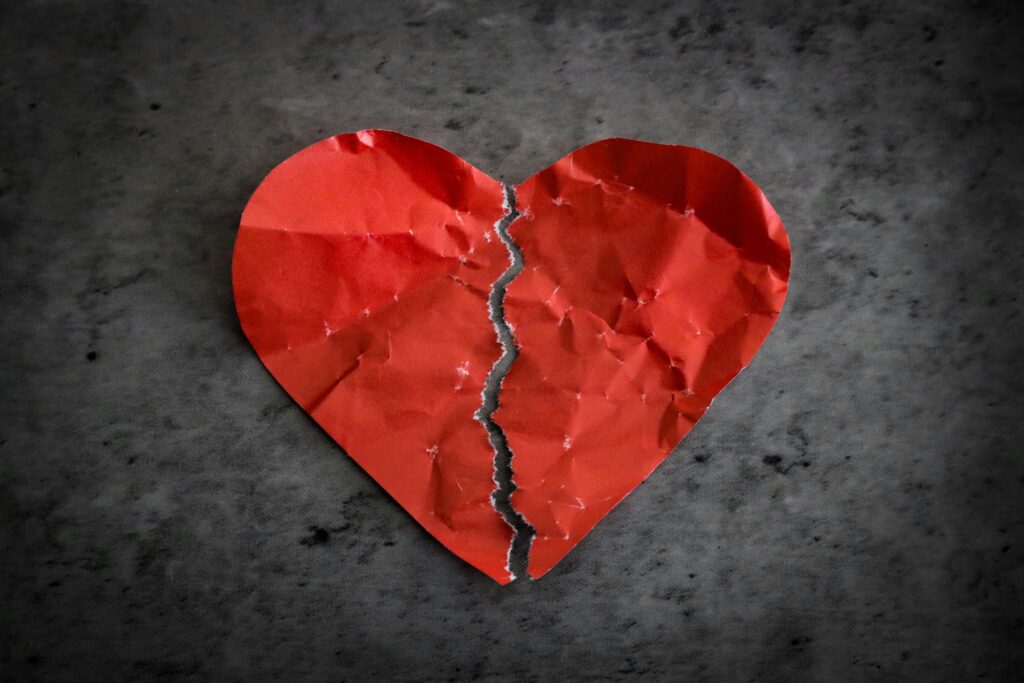 A torn red paper heart symbolizing heartbreak and lost romance.
