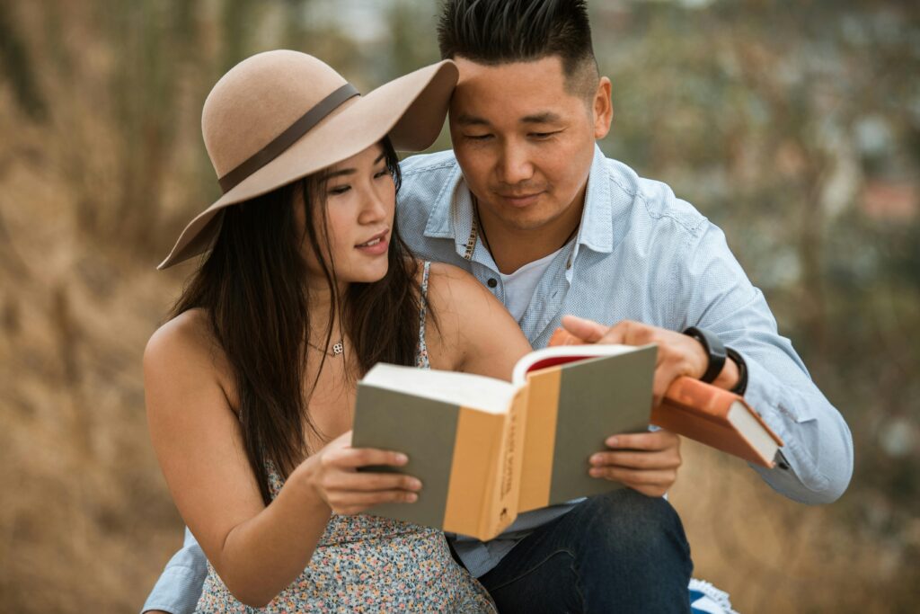 A couple enjoying a summer day outdoors, engrossed in reading books together.