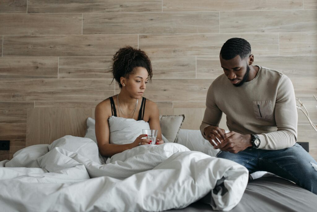 A supportive couple sitting in bed, comforting each other during illness indoors.